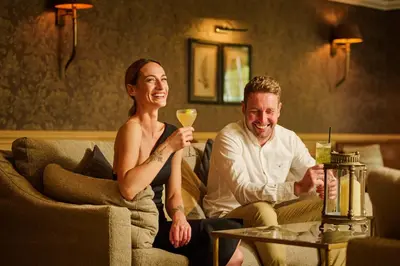 a man and a woman sitting on a couch with a wine glass at Cairn Lodge in Auchterarder