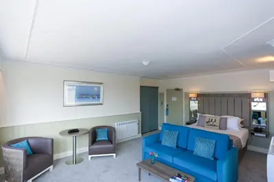 a hotel room with a blue couch and a bed at Duck Bay Hotel & Restaurant in Balloch