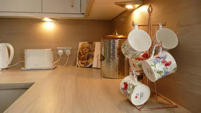 a kitchen counter with white dishes hanging from a wall at Riverside Apartments in Carluke