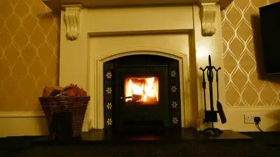 a fire burning in a fireplace in a room at Riverside Apartments in Carluke