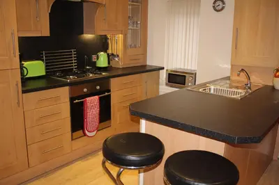 a kitchen with a counter and two stools in it at Nelson Seaside Apartment in Largs