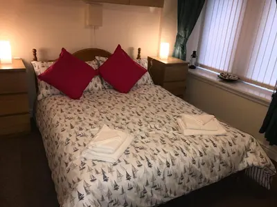 a bedroom with a bed with two towels on it at Nelson Seaside Apartment in Largs