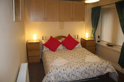 a bedroom with a bed with two red pillows at Nelson Seaside Apartment in Largs