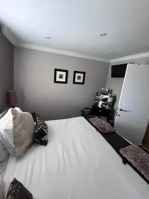 a bedroom with a white bed with three pictures on the wall at Gleneagles Lettings in Auchterarder