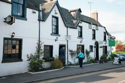 a woman walking down a street in front of a white building at Mains Farm in Stirling