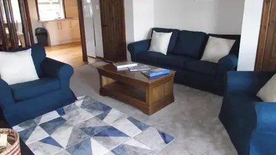 a living room with two blue couches and a coffee table at Craobh Marina Cottages in Craobh Haven