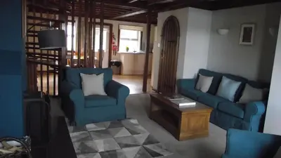 a living room with two blue chairs and a table at Craobh Marina Cottages in Craobh Haven