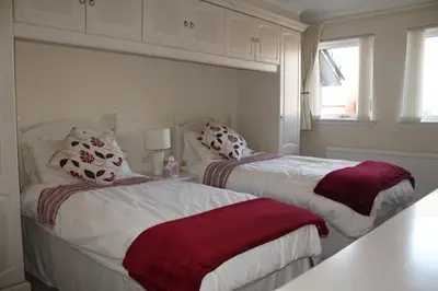 two beds in a bedroom with red and white sheets at Abbots Way in Ayr