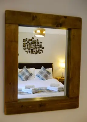 a mirror reflecting a bed with pillows in a bedroom at Birchbrae Highland Lodges in Onich