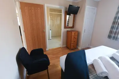 a bedroom with a bed and a chair and a television at Birchbrae Highland Lodges in Onich