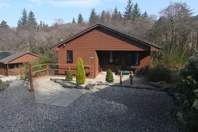 a wooden cabin with a porch and a fence at Birchbrae Highland Lodges in Onich