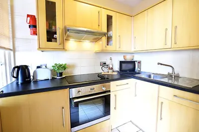 a kitchen with wooden cabinets and a sink at JOIVY Bohemian Writers Retreat in Old Town in Edinburgh