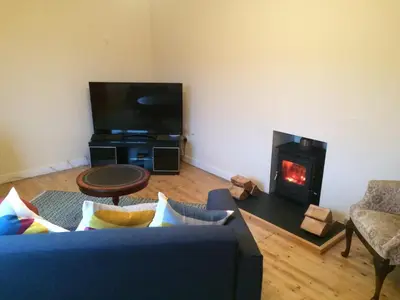 a living room with a blue couch and a fireplace at Ardminish House Gigha in Isle of Gigha