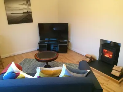 a living room with a blue couch and a fireplace at Ardminish House Gigha in Isle of Gigha
