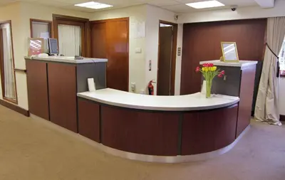 a lobby with a counter with a vase of flowers at The Burnside Hotel in Glasgow