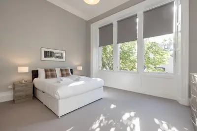 a white bedroom with a white bed and windows at Destiny Scotland - Q-Residence in Edinburgh
