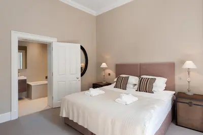 a bedroom with a large white bed and a bathroom at Destiny Scotland - Q-Residence in Edinburgh