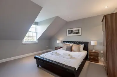 a bedroom with a large bed with a black leather couch at Destiny Scotland - Q-Residence in Edinburgh