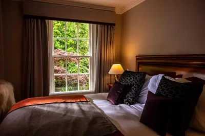 a bedroom with a bed with a large window at Knipoch House Hotel in Oban