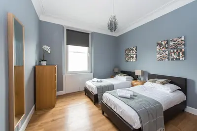 two beds in a room with blue walls at Castle apt, modern, CENTRAL in Edinburgh