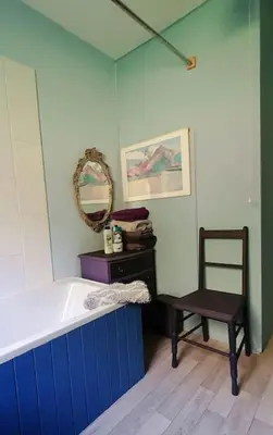 a bathroom with a tub and a chair and a mirror at Tobar nan Iasgair Lismore in Achnacroish