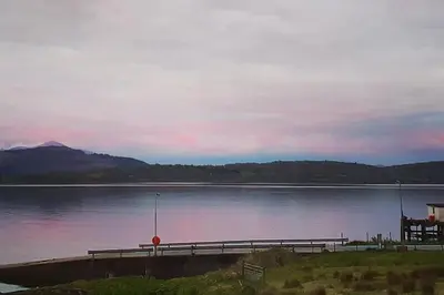 a dock on a body of water with a sunset at Tobar nan Iasgair Lismore in Achnacroish