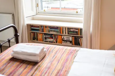 a bed with a stack of books in a window at Spacious & Unique city central 1 bed with WiFi in Edinburgh