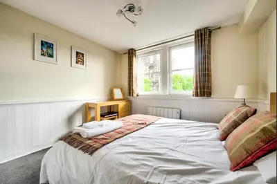 a bedroom with a large white bed with a window at Charming 1 Bed Apartment with Castle View in Edinburgh