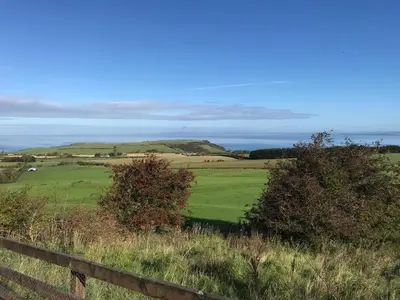 a green field with a fence and the ocean at Carrick Hills Cosy Croft STL SA-00137-F in Dunure