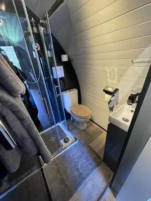 a bathroom with a shower and a toilet and a sink at Nevis Pod, West Highland Way Holidays in Kinlochleven