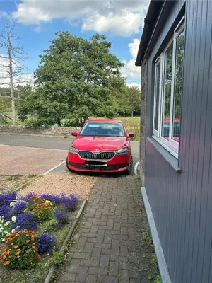 a red car parked next to a building with flowers at The Grey Cottage in Blackford