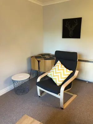 a living room with a chair and a table at The Grey Cottage in Blackford