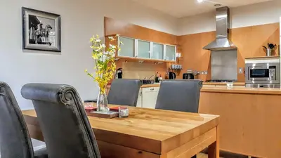 a kitchen with a wooden dining table and chairs at Elegant Apartment Near SECC/HYDRO in Finnieston, Glasgow in Glasgow