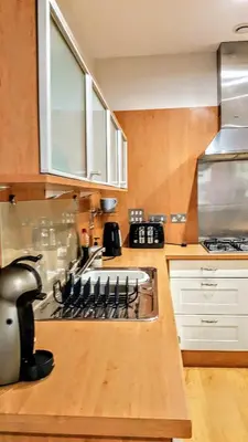 a kitchen with white cabinets and a stove top oven at Elegant Apartment Near SECC/HYDRO in Finnieston, Glasgow in Glasgow