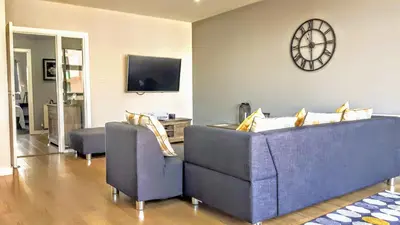 a living room with two couches and a clock on the wall at Elegant Apartment Near SECC/HYDRO in Finnieston, Glasgow in Glasgow