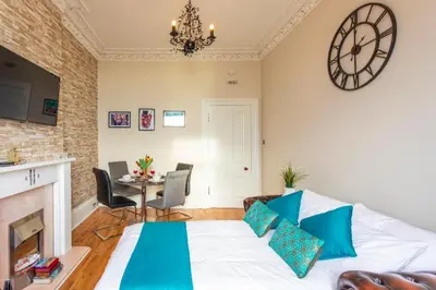 a living room with a bed and a clock on the wall at Clyde View Apartment in Helensburgh
