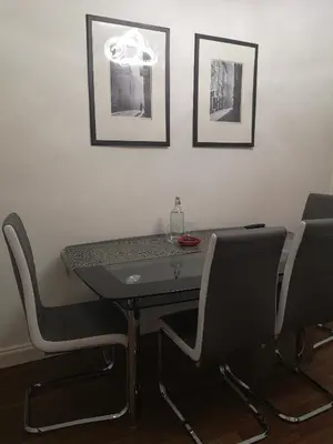 a dining room table with two chairs and a table and two pictures at Sleep Well Apartment in Glasgow