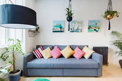 a living room with a blue couch with colorful pillows at The Plywood Flat, Modern Style In A Traditional Tenement in Edinburgh