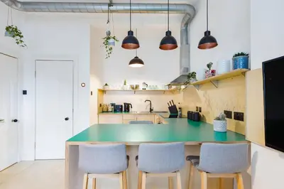 a kitchen with a green counter and chairs at The Plywood Flat, Modern Style In A Traditional Tenement in Edinburgh