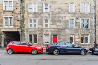 two cars parked in a parking lot in front of a building at The Plywood Flat, Modern Style In A Traditional Tenement in Edinburgh