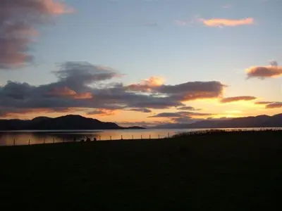 a sunset over a body of water with a field at Highland Croft B&B in Onich