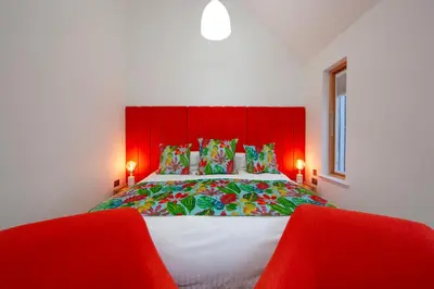 a bedroom with a red headboard and a bed with two red chairs at Ardtorna in Benderloch