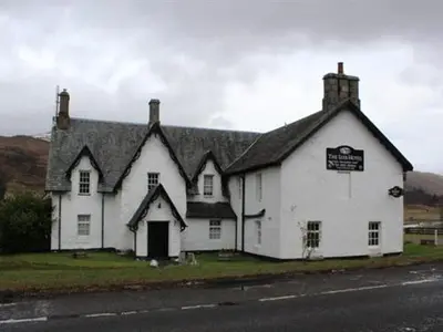a white house with a black roof on the side of a road at Luib Hotel in Killin