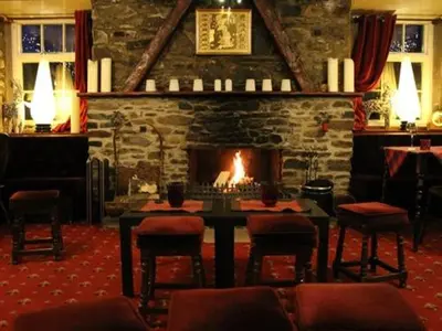 a room with a fireplace and a table and chairs at Luib Hotel in Killin