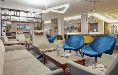 a waiting room with blue chairs and a table at Hampton By Hilton Edinburgh Airport in Ingliston