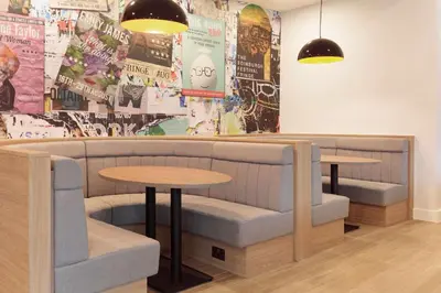 a restaurant with couches and tables and posters on the wall at Hampton By Hilton Edinburgh Airport in Ingliston