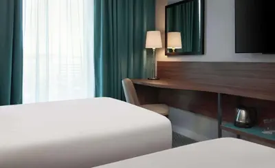 a hotel room with two beds and a desk with a mirror at Hampton By Hilton Edinburgh Airport in Ingliston