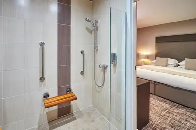 a bathroom with a shower and a bed in a room at The Ranald Hotel in Oban