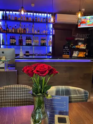 a vase with a red rose in it on a table at The Ranald Hotel in Oban