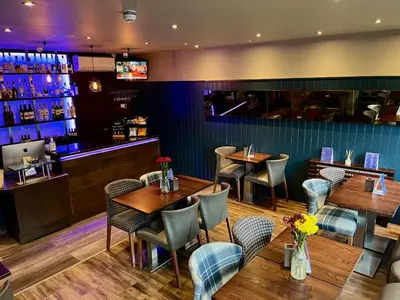 a restaurant with tables and chairs and a bar at The Ranald Hotel in Oban